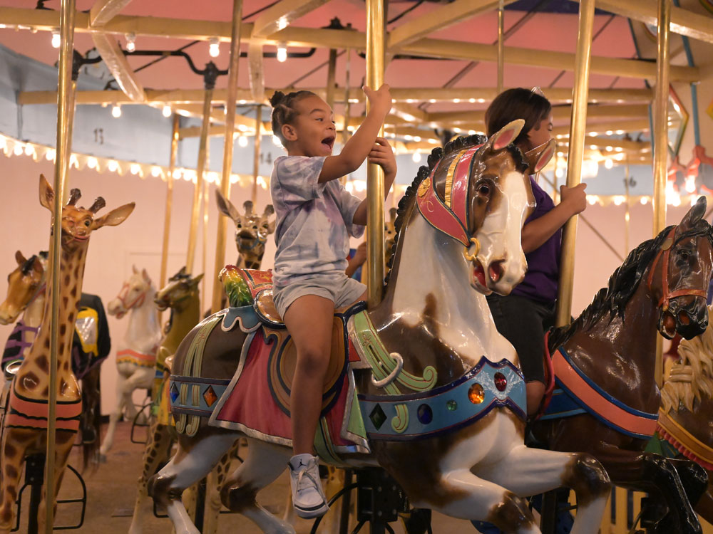 Laughing girl riding Carousel horse.